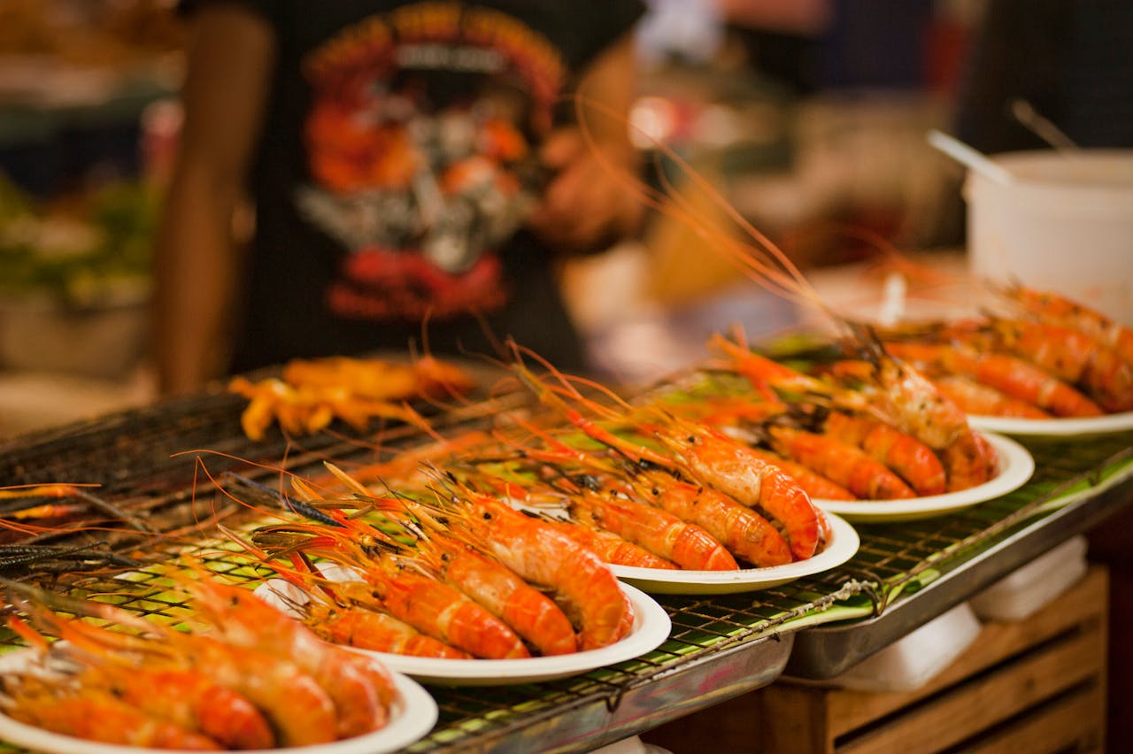 Deliciously grilled shrimps on plates ready to serve at a vibrant Bangkok street food market.